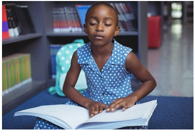 Girl using Braille to read a book